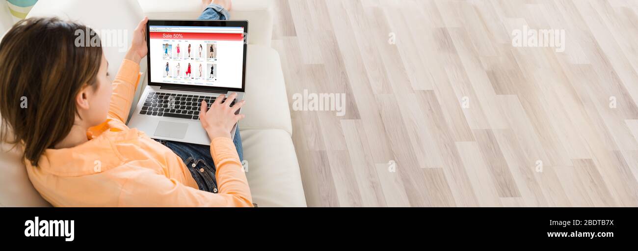 Donna Surfing Online su laptop su divano e Shopping Online Foto Stock