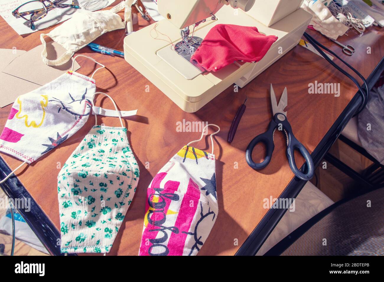 Una pila di maschere cucite in tessuto con motivi colorati. La gente sta facendo maschere per coprire la mancanza di forniture di DPI per gli ospedali. Foto Stock