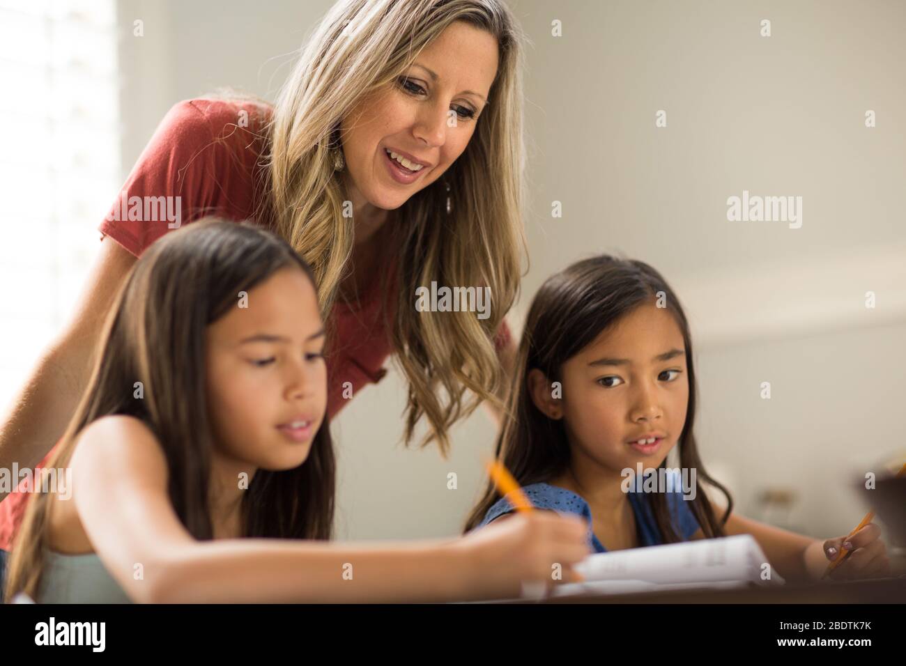 Madre Che Aiuta Le Sue Figlie Con La Loro Homework Foto Stock