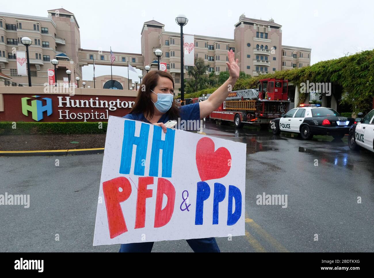 Los Angeles, California, Stati Uniti. 9 Aprile 2020. Un operatore sanitario in possesso di un cartello saluta mentre il personale della polizia e del reparto antincendio di Pasadena si accingono davanti all'Huntington Hospital con luci di emergenza e sirene attivate per mostrare apprezzamento agli operatori sanitari nella sala di emergenza e in tutto l'ospedale di Pasadena, California, giovedì 9 aprile 2020. Credit: Ringo Chiu/ZUMA Wire/Alamy Live News Foto Stock