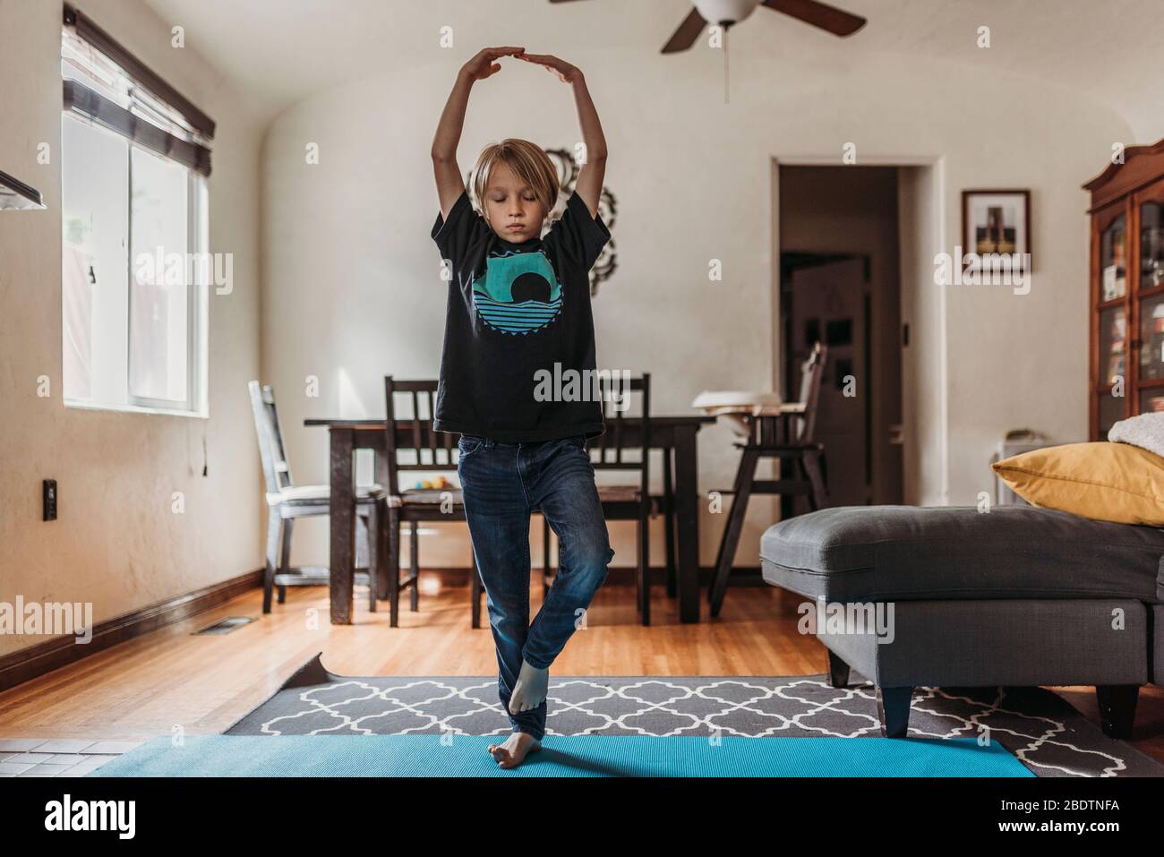 Ragazzo che fa yoga in soggiorno durante l'isolamento Foto Stock