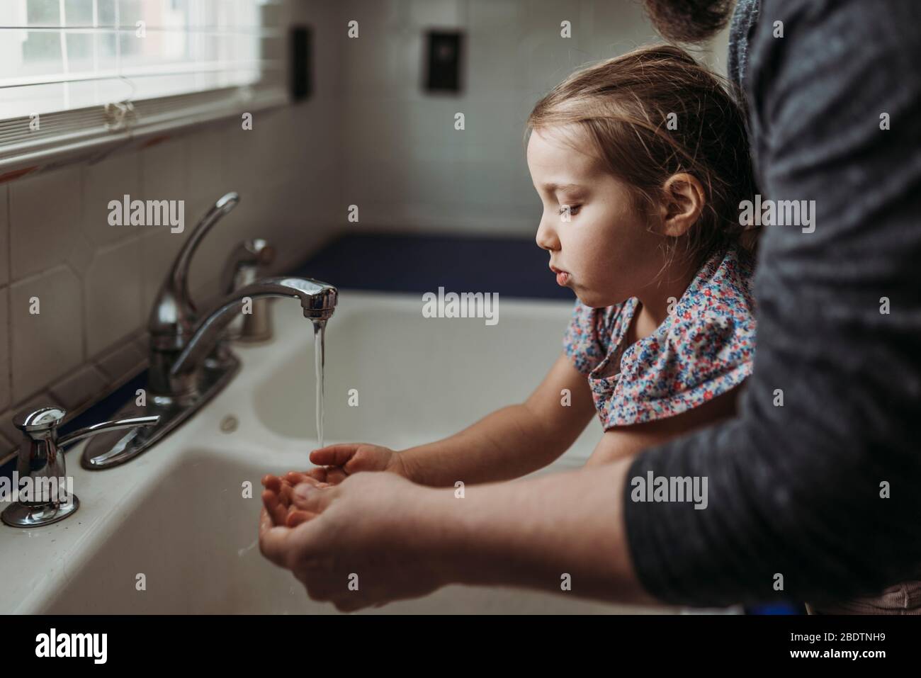 Vista laterale della ragazza giovane che ha le mani lavate da papà Foto Stock