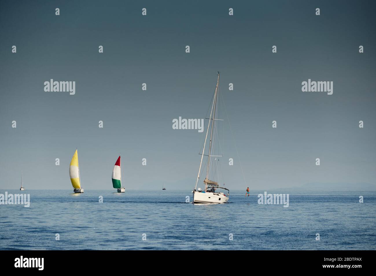 I membri del team hanno un buon tempo dopo il completamento della gara e tuffarsi in acqua da una corda su un albero, la corsa di barche a vela, intensa competizione Foto Stock