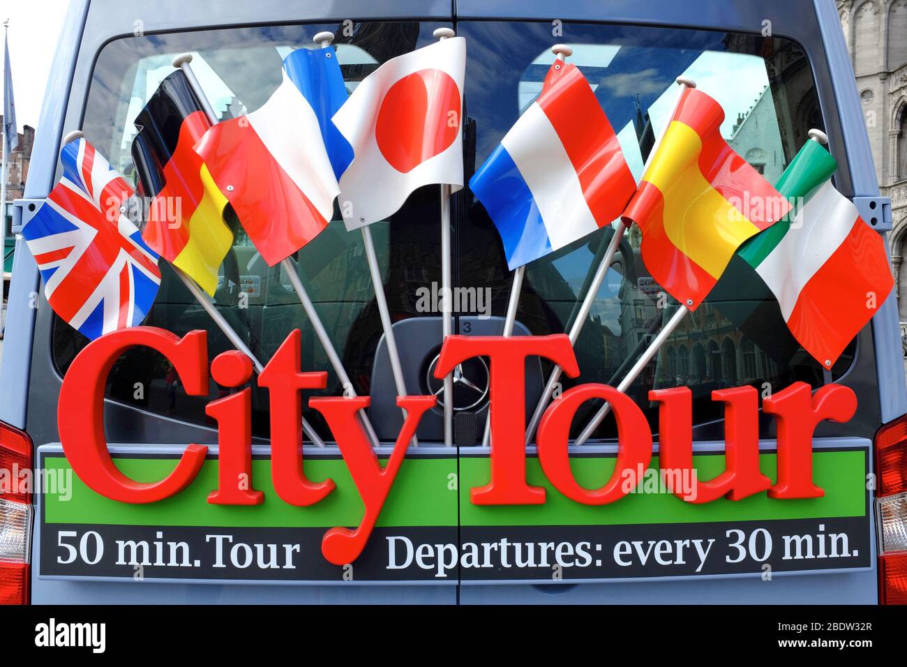 Un autobus turistico della città decorato con bandiere di diverse nazioni.Bruges.Fiandre Occidentali.Belgio Foto Stock