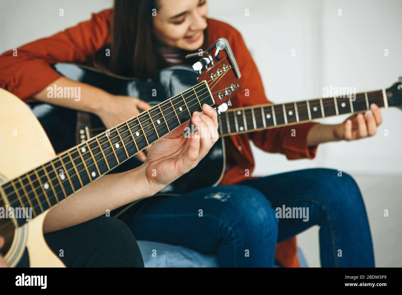 Imparare a suonare la chitarra. L'insegnante spiega allo studente le basi per suonare la chitarra. Lezioni individuali di scuola domestica o extracurricolare. Foto Stock