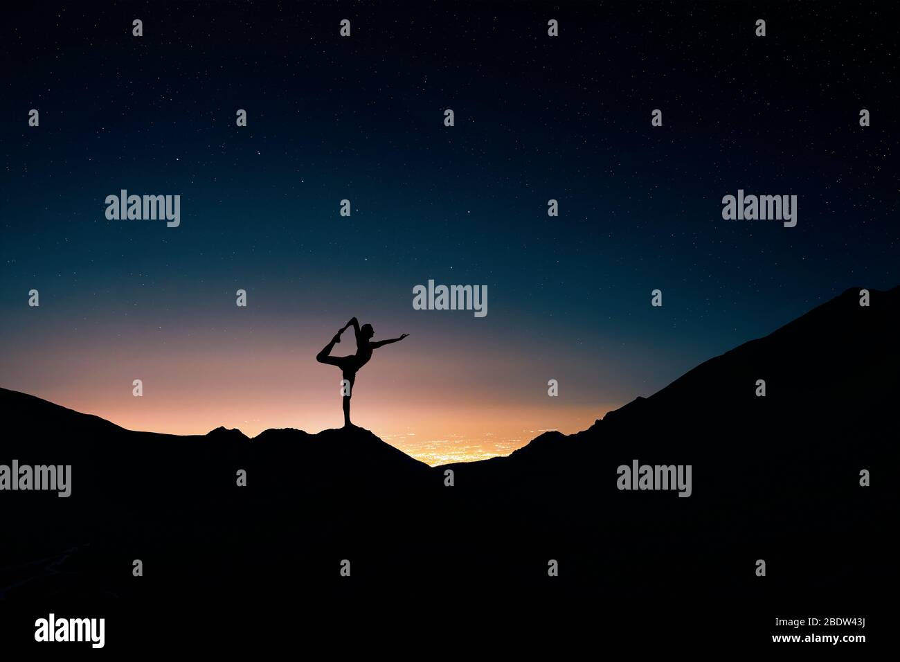 Montare l'uomo in silhouette fare yoga natarajasana pongono alla città di notte e il cielo stellato sfondo Foto Stock