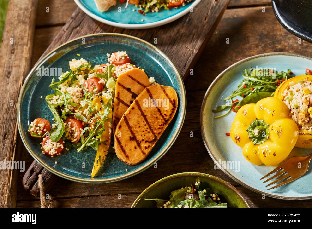 Un primo piano di vari piatti gourmet vegetariani su un rustico tavolo di legno. Foto Stock