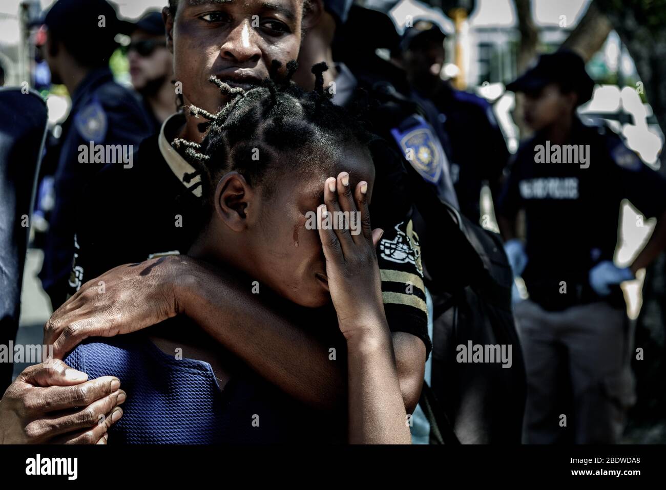 Una madre conforta sua figlia durante l'evasione della polizia di profughi stranieri africani indigenti dal CBD di Città del Capo in Sudafrica Foto Stock
