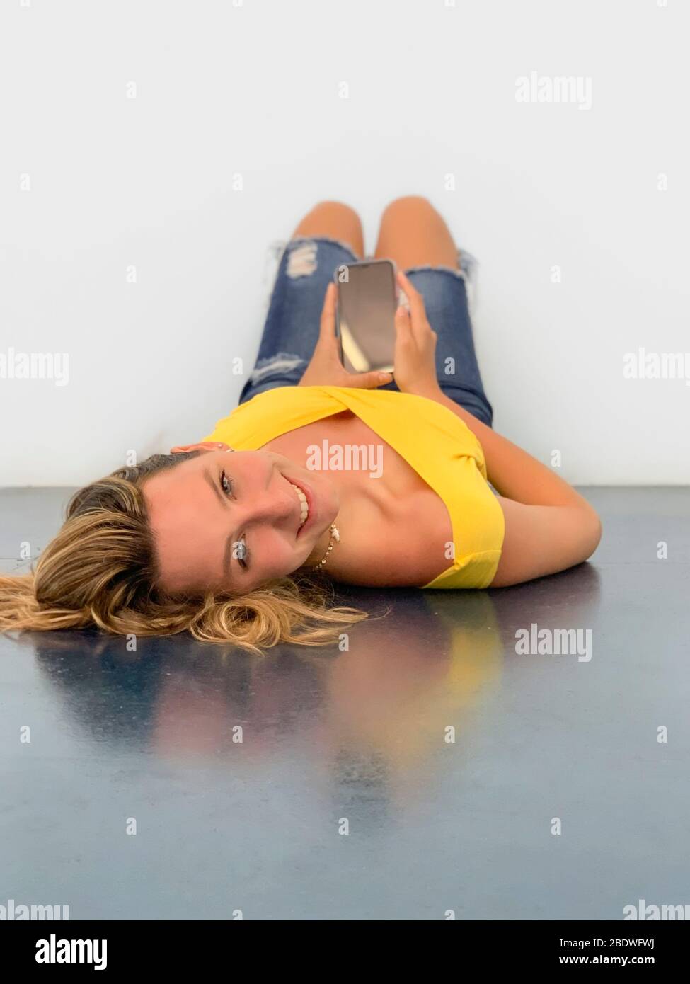 Giovane donna sdraiata sul pavimento con mobile Foto Stock