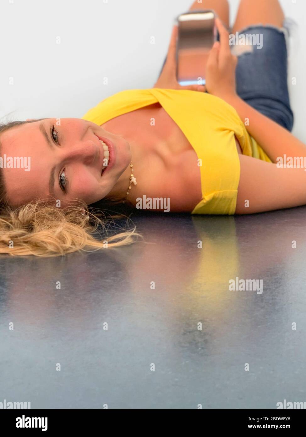 Giovane donna sdraiata sul pavimento con mobile Foto Stock