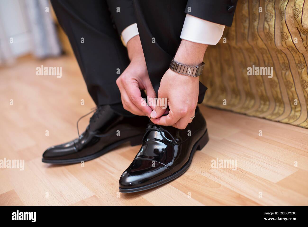Vista in primo piano delle mani maschili allacciando bellissime scarpe  eleganti. Giorno di nozze. Cravatta lo sposo la sua scarpa . Uomo che  indossa una tuta indossando le scarpe marroni. Mani e