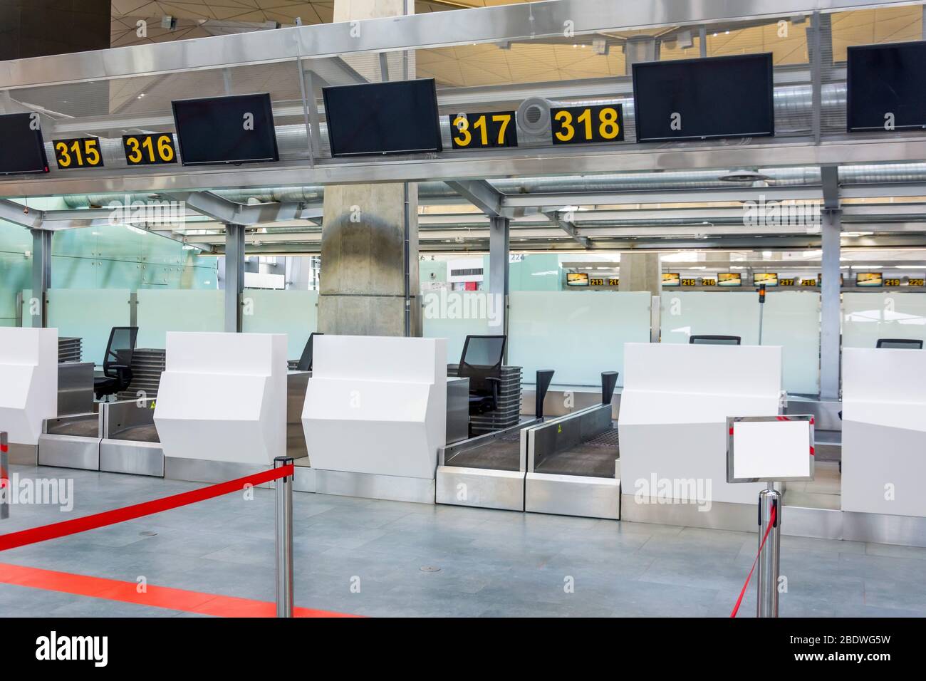 Banchi di check-in vuoti per la consegna dei bagagli con percorsi annullati con  nastro rosso per differenziare i passeggeri al terminal dell'aeroporto Foto  stock - Alamy
