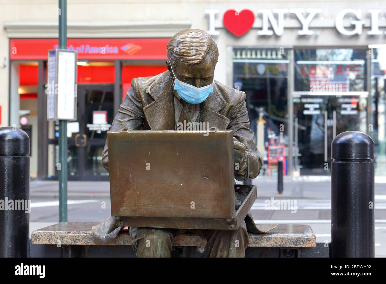 La statua dell'uomo d'affari 'Double Check' con una maschera facciale come simbolo dell'attuale pandemia del coronavirus COVID-19 a New York, NY. Foto Stock
