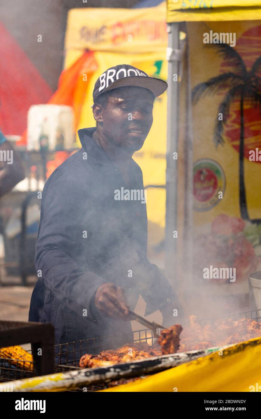 Ritratto di un uomo che cucina pollo jerk al Notting Hill Carnival, Londra Foto Stock