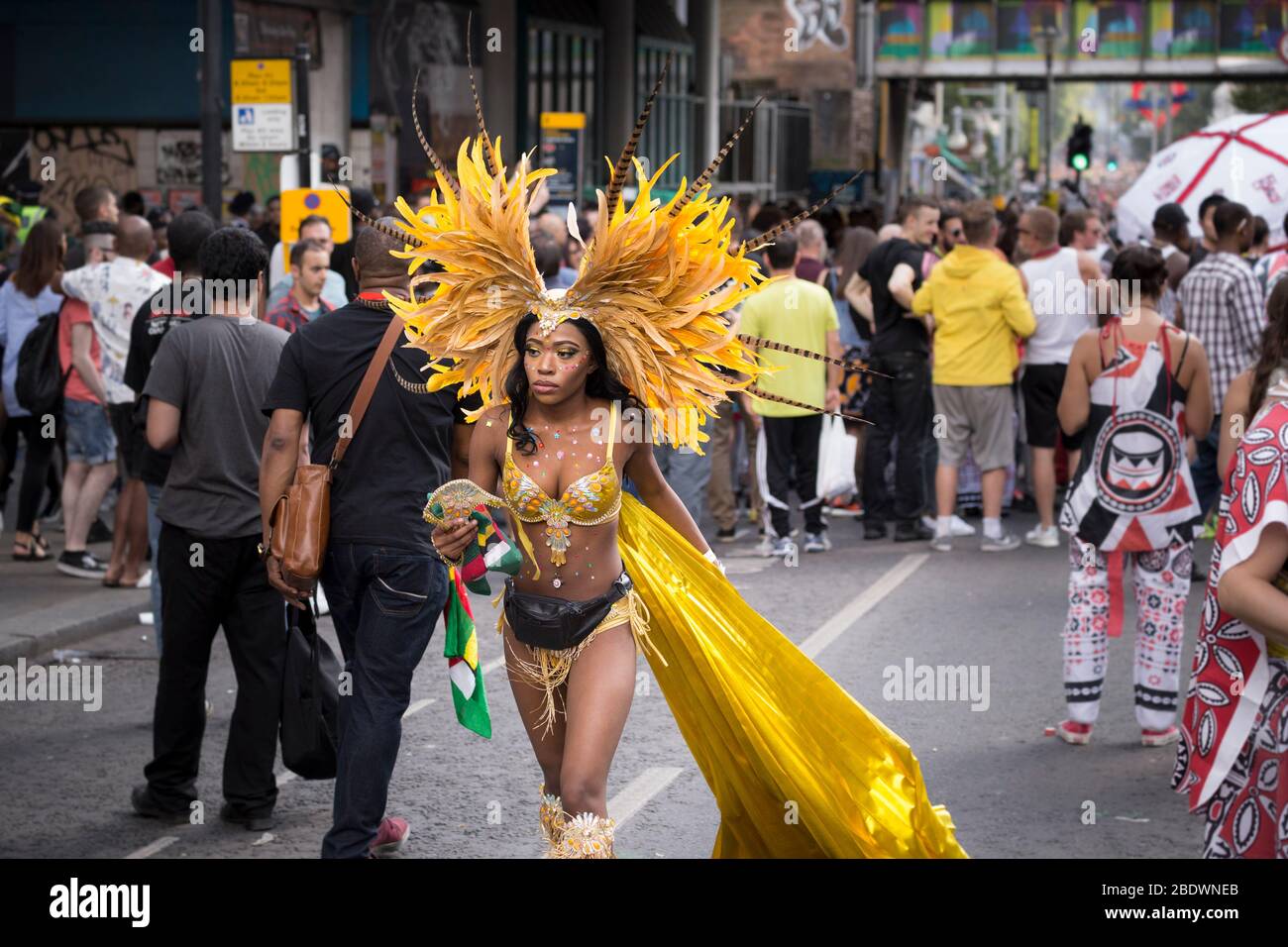 Interprete in costume giallo camminando lungo una strada al Notting Hill Carnival, Londra Foto Stock