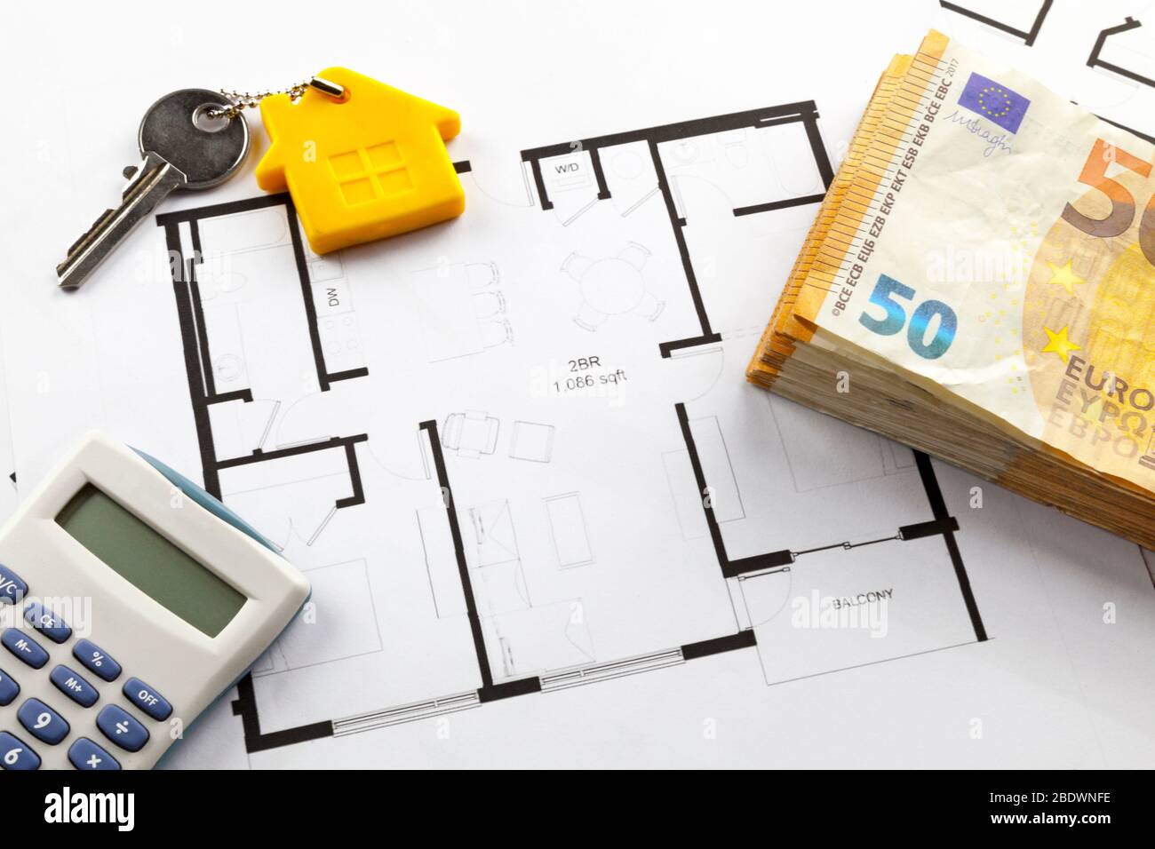 Alcune banconote in euro, una calcolatrice e una chiave di casa in cima ai piani di costruzione. Foto Stock