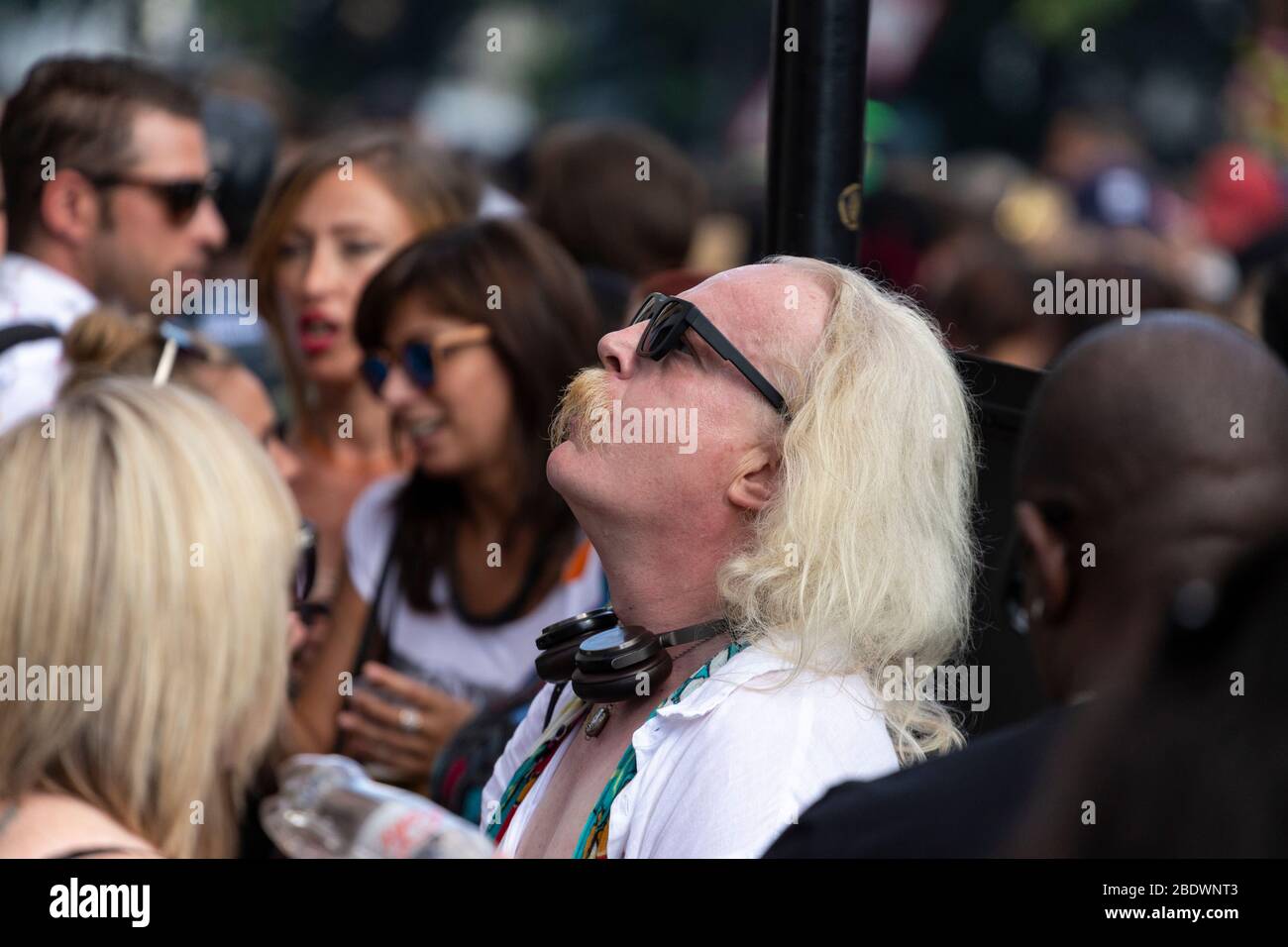 Ritratto di un uomo con lunghi capelli grigi e occhiali da sole che guarda al Notting Hill Carnival, Londra Foto Stock