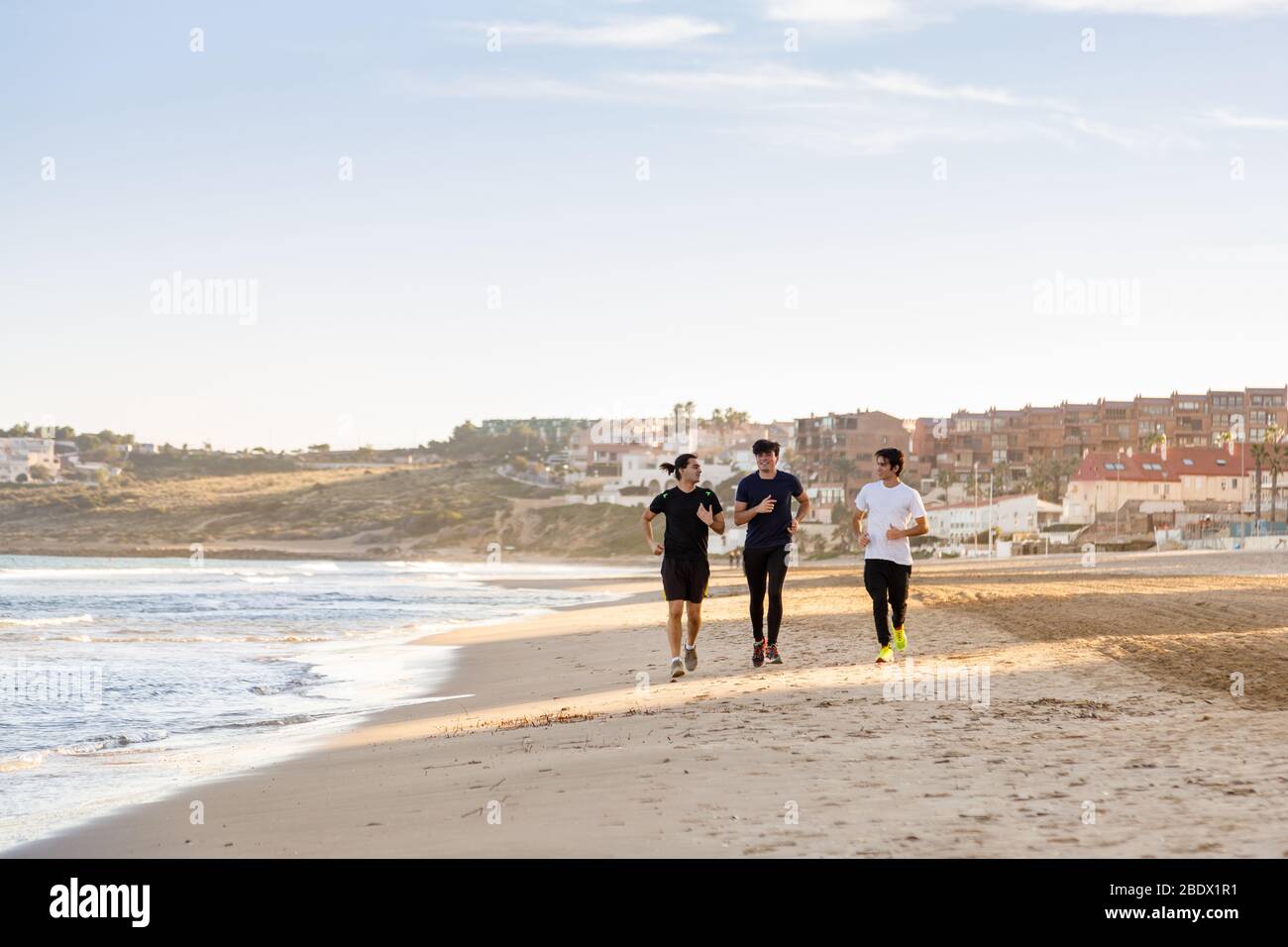 Tre ragazzi che corrono lungo la spiaggia Foto Stock