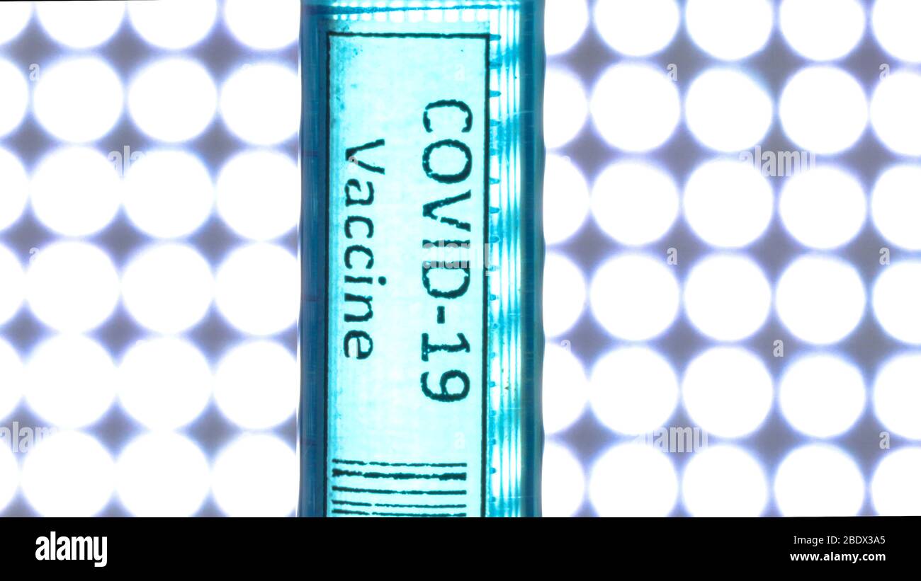 Una siringa per vaccino contro il coronavirus COVID-19 all'interno della camera illuminata di colore blu con il liquido chimico all'interno Foto Stock