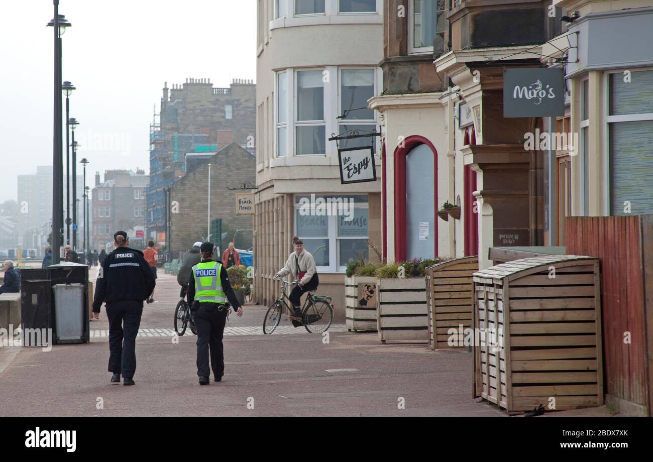 Pattugliamenti di polizia su una spiaggia molto tranquilla di Portobello e Promenade, Edimburgo, Scozia, Regno Unito. 10 aprile 2020. Nella foto: Pattugliamenti della polizia sul lungomare, tre separati prima di mezzogiorno nell'arco di un'ora. Il segno dice Benvenuto ma non questo fine settimana di Pasqua. Foto Stock