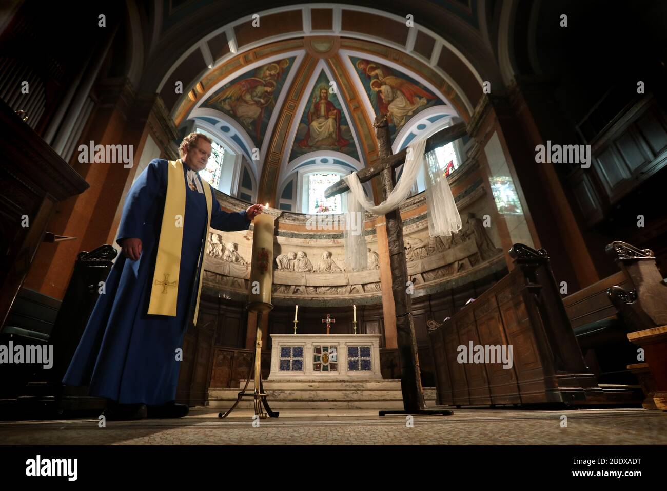 Il Rev Peter Sutton accende la candela di Pasqua mentre registra il sermone della Domenica di Pasqua nel Santuario principale alla Chiesa Parrocchiale di San Cuthbert a Edimburgo, la chiesa è stato streaming sermoni mentre il Regno Unito continua in blocco per contribuire a frenare la diffusione del coronavirus. Foto Stock