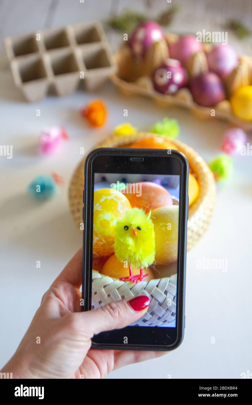 Donna che prende la foto sul suo smartphone di uova di Pasqua e decorazioni. Foto Stock
