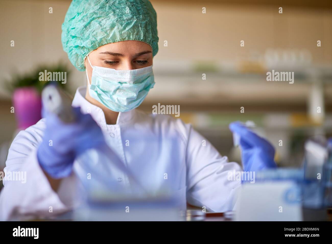 Donna al lavoro con indumenti protettivi che lavora in laboratorio di bichemistry Foto Stock