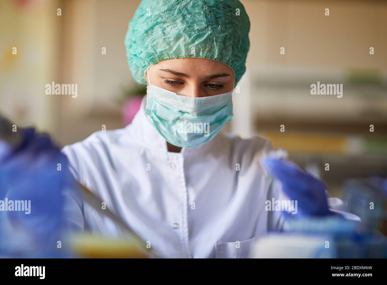 Donna con equipaggiamento protettivo che lavora in laboratorio biochimico Foto Stock
