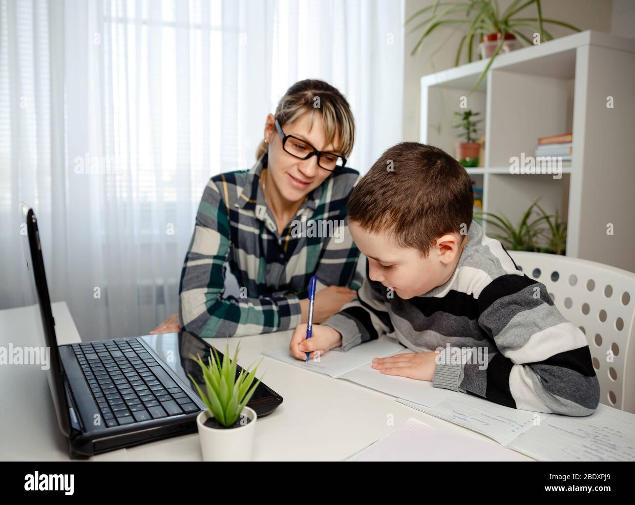 Bambino che fa i compiti con la madre. Famiglia a casa. Apprendimento a casa, apprendimento online, concetto di auto-quarantena Foto Stock
