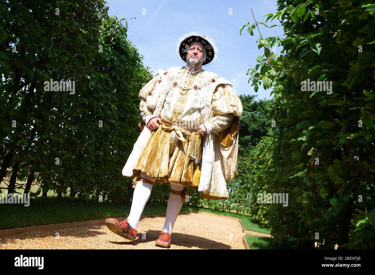 Un attore, vestito da Re Enrico l'ottavo, passeggerà lungo un sentiero nei giardini del Palazzo di Hampton Court. Foto Stock