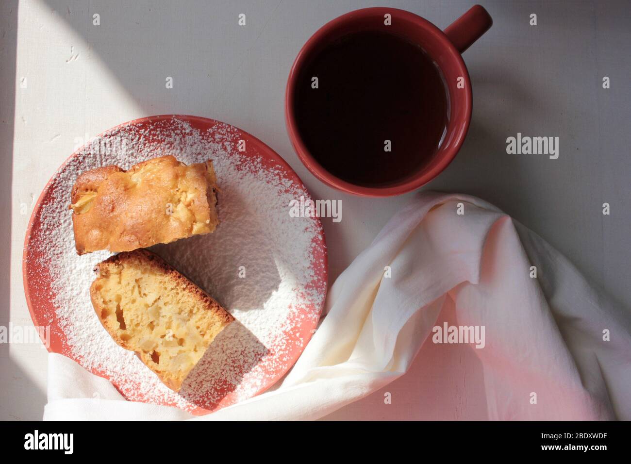 Tradizionale budino di mela di Charlotte appena sfornato in teglia e su un piatto con zucchero in polvere. Torta leggera e una tazza di tè per la colazione. Foto Stock