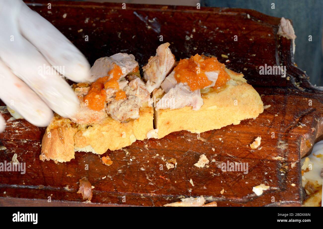 Primo piano shot di chef consegnare il tipo di cibo di bruchetta fresco preparato sul tagliere costituito da una diffusione di carni e verdure miste su una fetta Foto Stock