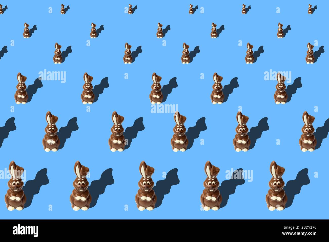 Motivo pasquale alla moda fatto di conigli di cioccolato su sfondo blu in stile minimal. Concetto pasquale in stile minimale. Foto Stock