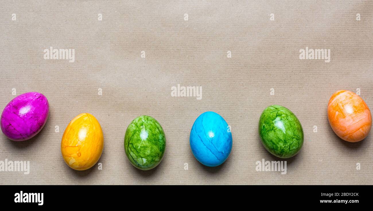 Bordo delle uova di pasqua in diversi colori sul fondo su uno sfondo di carta marrone Foto Stock