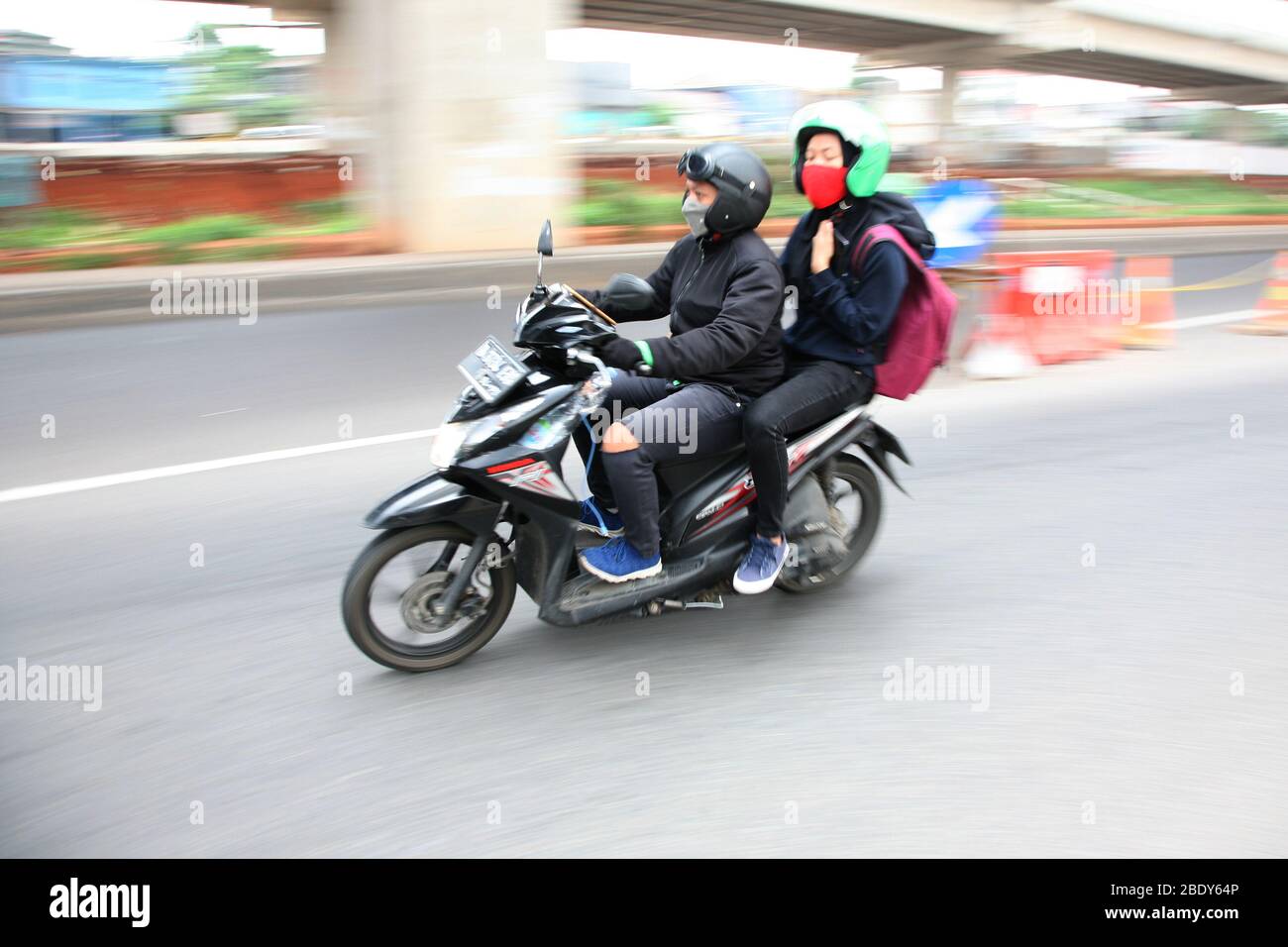 Giacarta, Indonesia. 10 aprile 2020. I motociclisti privati possono ancora viaggiare insieme ai passeggeri, sia il conducente che il passeggero devono indossare maschere e guanti, durante l'attuazione delle restrizioni sociali su larga scala (PSBB) nella regione della capitale speciale di Giacarta. Mentre il trasporto a due ruote basato su applicazione è limitato all'uso consentito solo per il trasporto di merci. (Foto di Kuncoro Widyo Rumpoko/Pacific Press) Credit: Pacific Press Agency/Alamy Live News Foto Stock