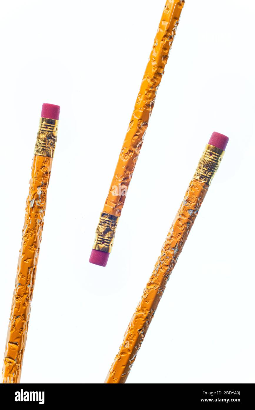 Colpo verticale della fine della gomma di tre matite masticate. Due provengono dall'angolo inferiore sinistro e l'altra matita dall'angolo superiore destro. Foto Stock