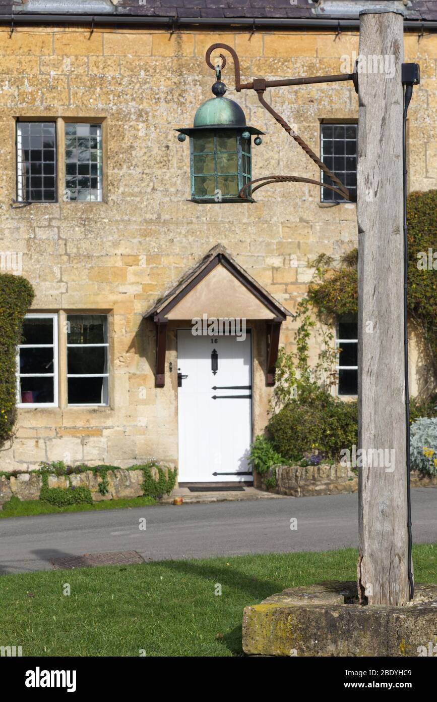 Lampada d'epoca su un palo di legno incorporato in una pietra nel villaggio di Stanton Foto Stock