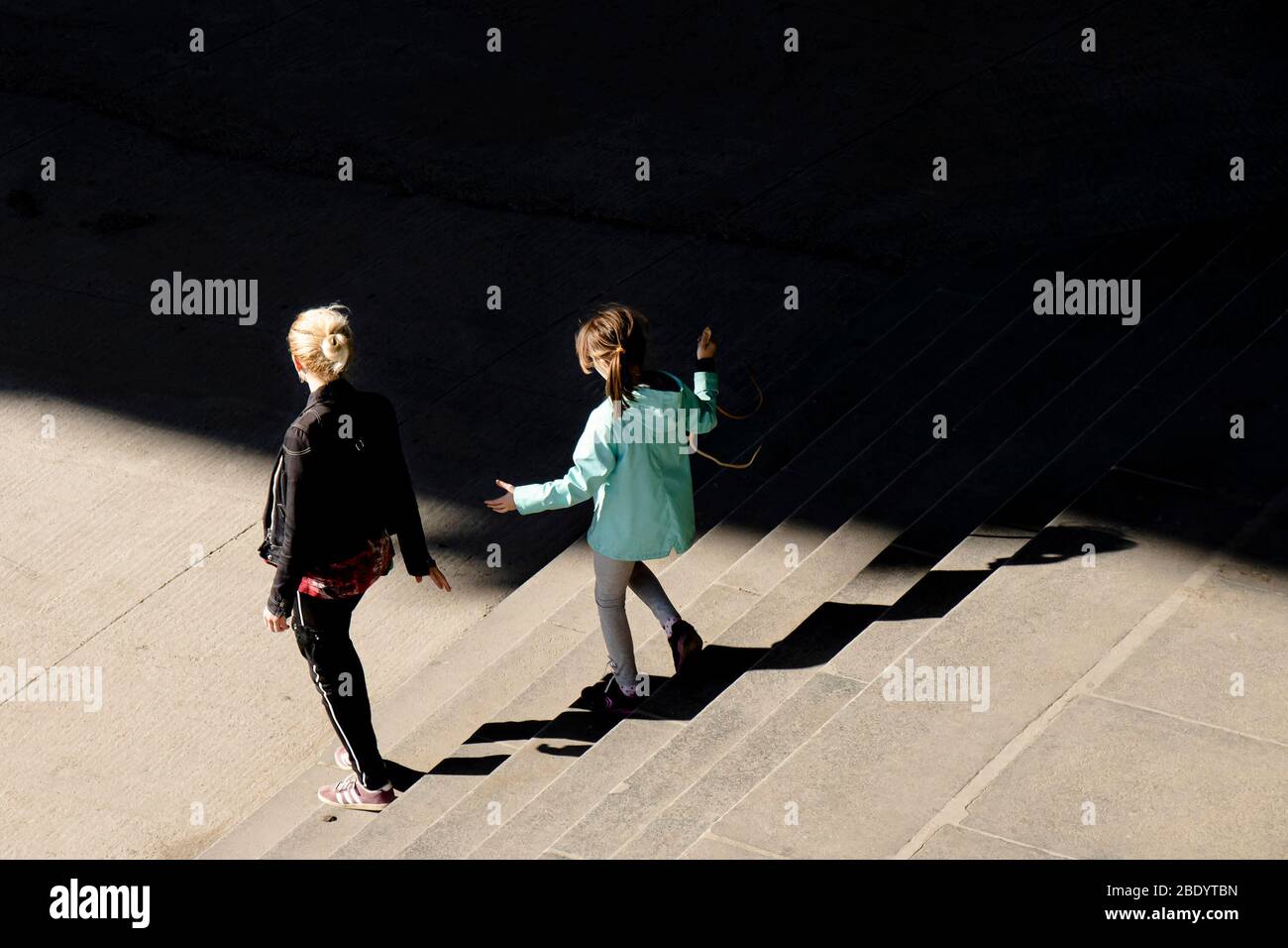Belgrado, Serbia - 18 marzo 2020: Una giovane donna e una ragazza camminano giù per le scale pubbliche della città mentre si allungano per tenere le mani l'un l'altro Foto Stock