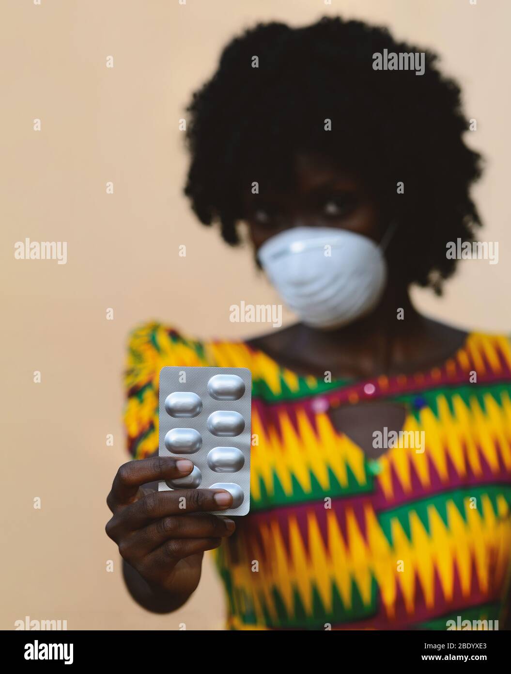Crisi del virus in tutto il mondo: African Woman Upper Body Shot con maschera e pillole medicamentoso Foto Stock