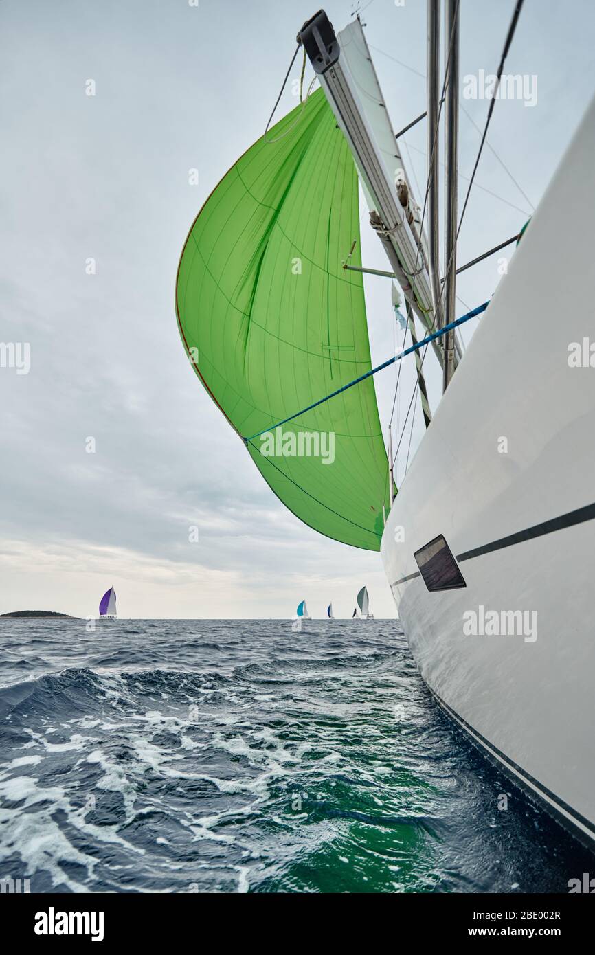 Croazia, Mare Adriatico, 19 settembre 2019: La corsa delle barche a vela, la squadra si siede sul bordo di una barca a bordo, colori brillanti, vista dei partecipanti Foto Stock