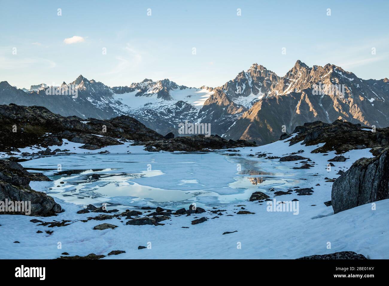 All'inizio di luglio nelle montagne Talkeetna dell'Alaska. Il lago alpino inizia a scongelare e i ghiacciai punteggiano le lontane vette rocciose. Foto Stock