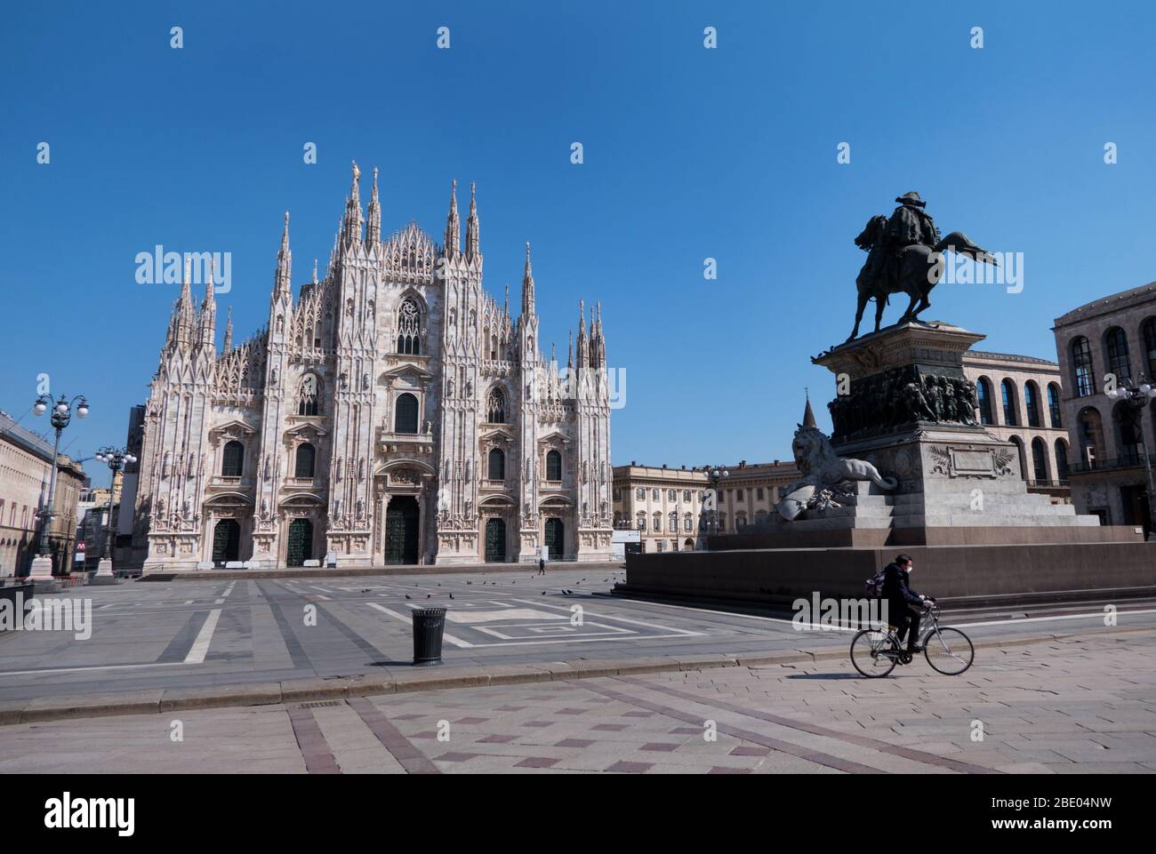 Vista di una Piazza Duomo deserta a Milano, durante la quarantena COVID-19 con uomo in bicicletta che indossa la maschera facciale. Milano, città italiana e coronavirus Foto Stock