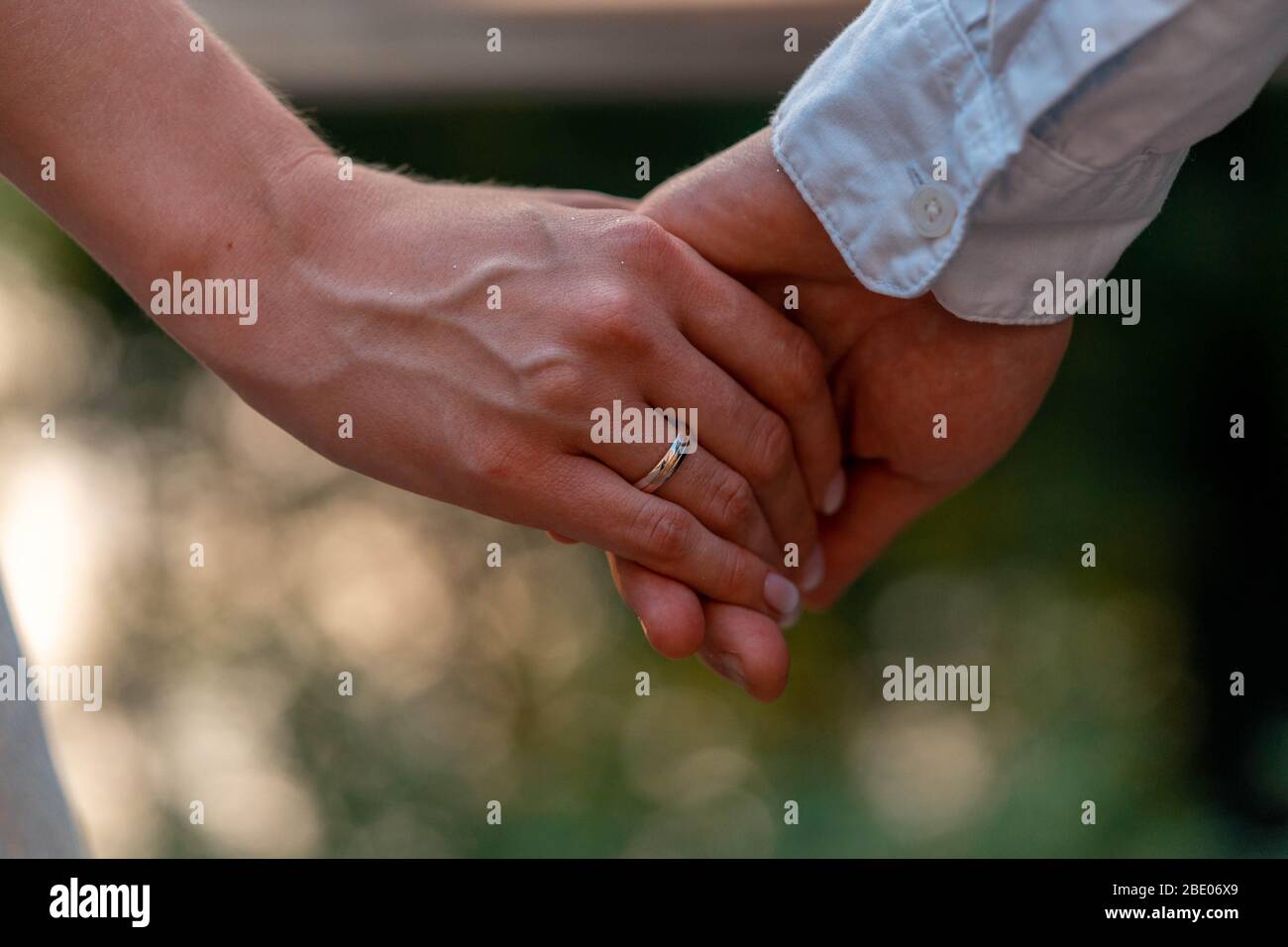 Primo piano di Bride e di tenere la Grroom mani con Wedding anelli su di esso. Dare degli anelli e dei voti di nozze all'aperto. Matrimonio nel Parco. Foto Stock