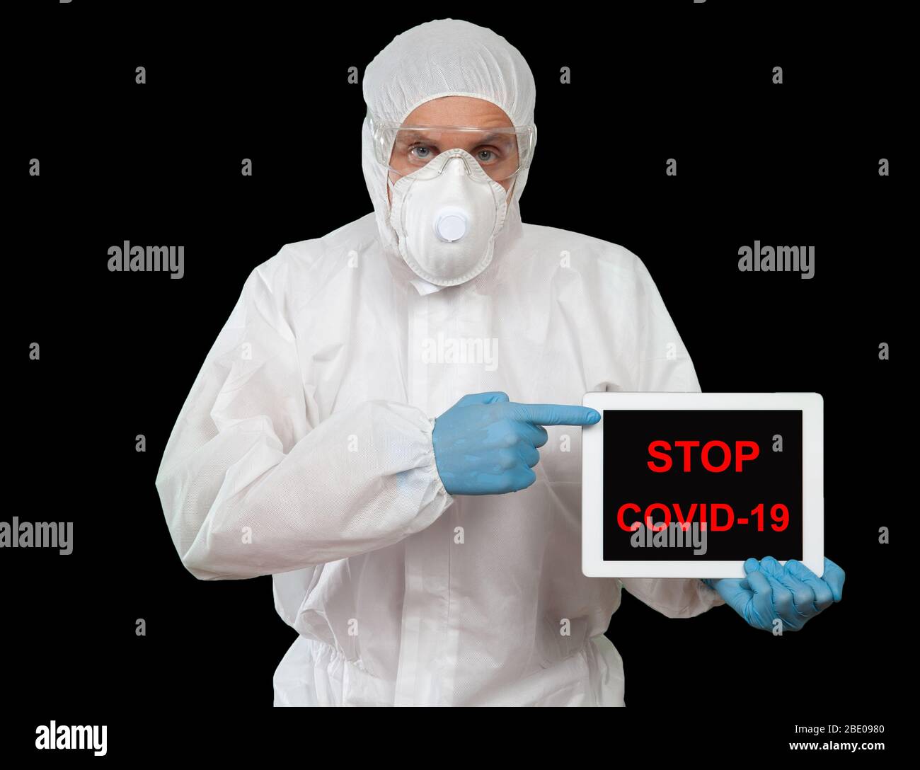 Un medico che indossa indumenti protettivi visualizza il tablet digitale con il messaggio COVID-19 Foto Stock