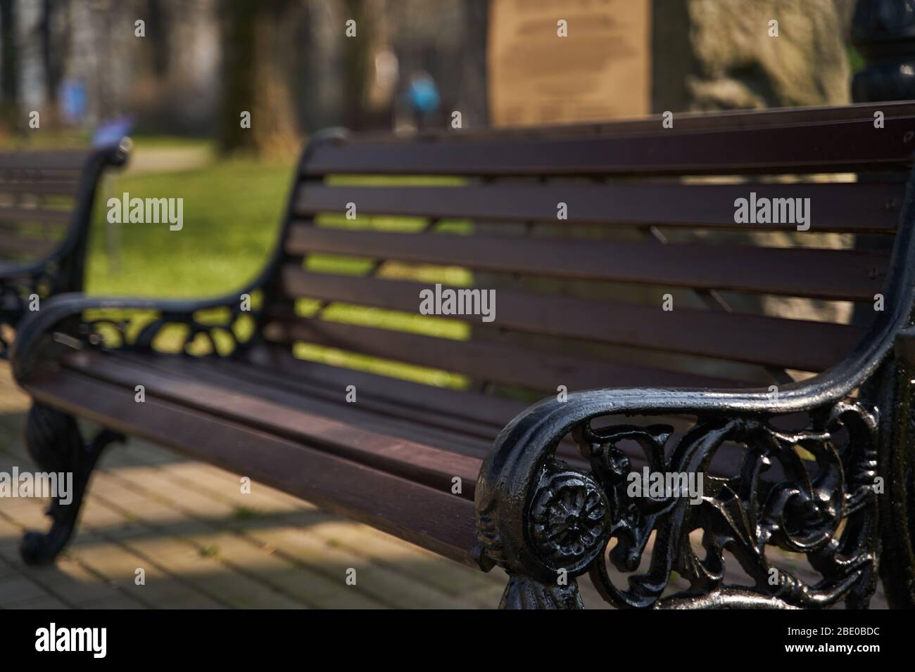 panca in legno con gambe in ferro intagliato in ambiente urbano Foto Stock