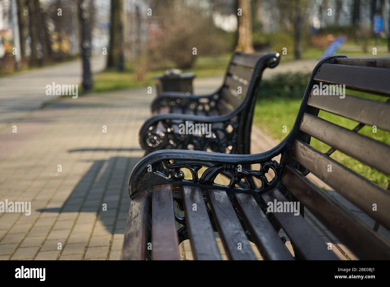 panca in legno con gambe in ferro intagliato in ambiente urbano Foto Stock