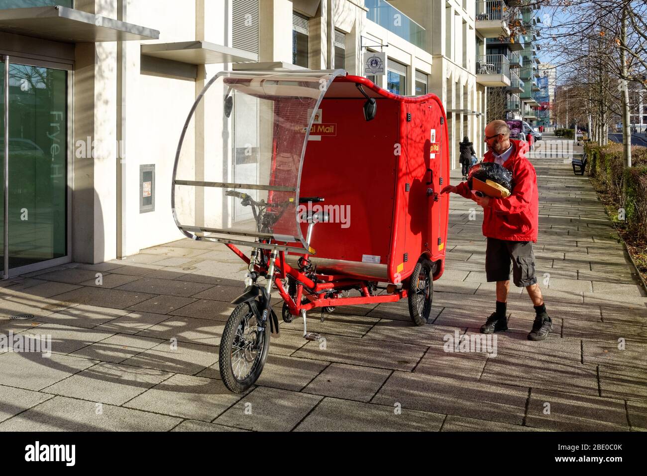 Ciclismo Royal Mail postman su bici elettrica cargo, e-Trike, alimentato da una combinazione di energia solare, batteria, pedale e freno tecnologia Stratford Londra UK Foto Stock