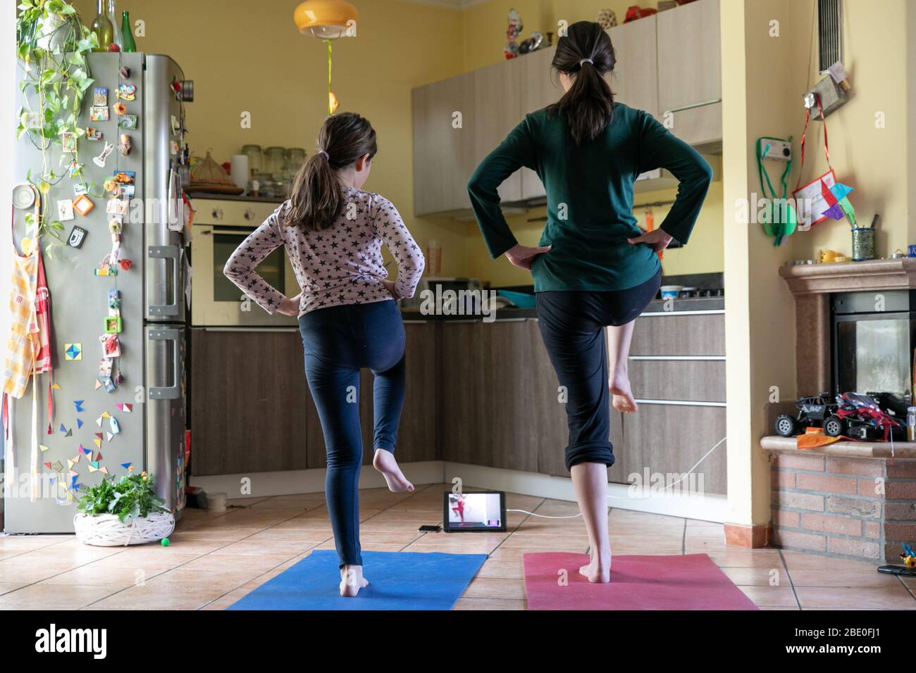 Madre e figlia che fanno esercizi di yoga su tappeti colorati a casa durante la quarantena Foto Stock