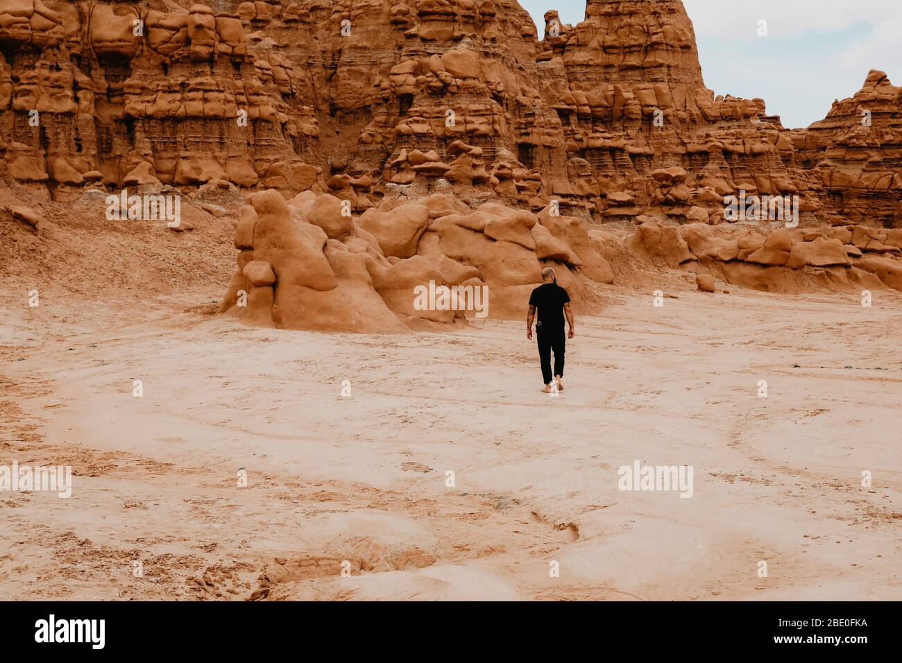 Uomo che cammina da solo tra le rocce di Hoodoo nella valle di Goblin Foto Stock
