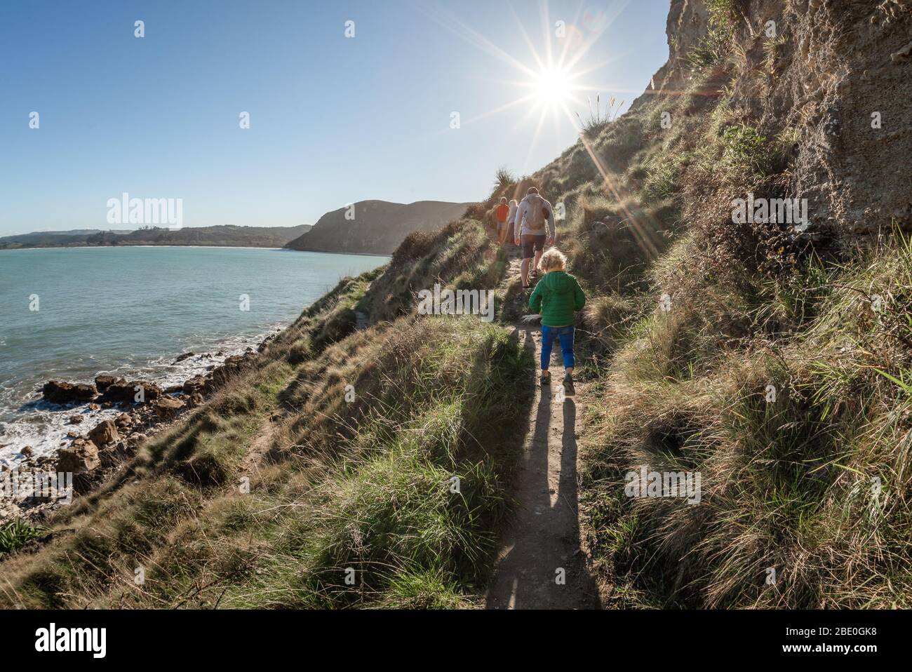Padre e bambini escursioni sul sentiero di montagna sul mare in Nuova Zelanda Foto Stock
